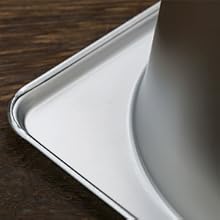 Gros plan d'un coin de plaque à pâtisserie en métal, montrant son bord incurvé et sa surface brillante sur fond en bois