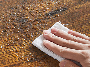 une personne nettoyant une table en bois avec un chiffon.