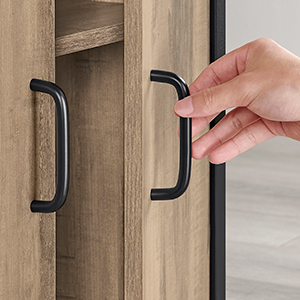 une main tenant une poignée noire sur une porte d'armoire en bois.