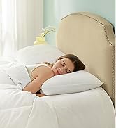 comprenant une tête de lit rembourrée beige avec bordure décorative à clous, une literie blanche et des oreillers moelleux dans une chambre lumineuse et aérée