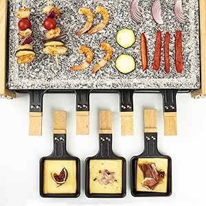 Vue aérienne d'un appareil à raclette avec des légumes et des viandes grillés sur une plaque supérieure en pierre, trois petites casseroles noires contenant du fromage fondu et de la viande en dessous.