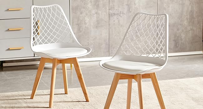 Deux chaises de salle à manger modernes dotées de sièges à motifs géométriques blancs, de pieds en bois et de sièges rembourrés contre un mur d'aspect béton