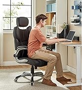 Personne travaillant à domicile avec un ordinateur portable, assise dans une chaise de bureau ergonomique noire avec appui-tête contre un système de rangement mural organisé