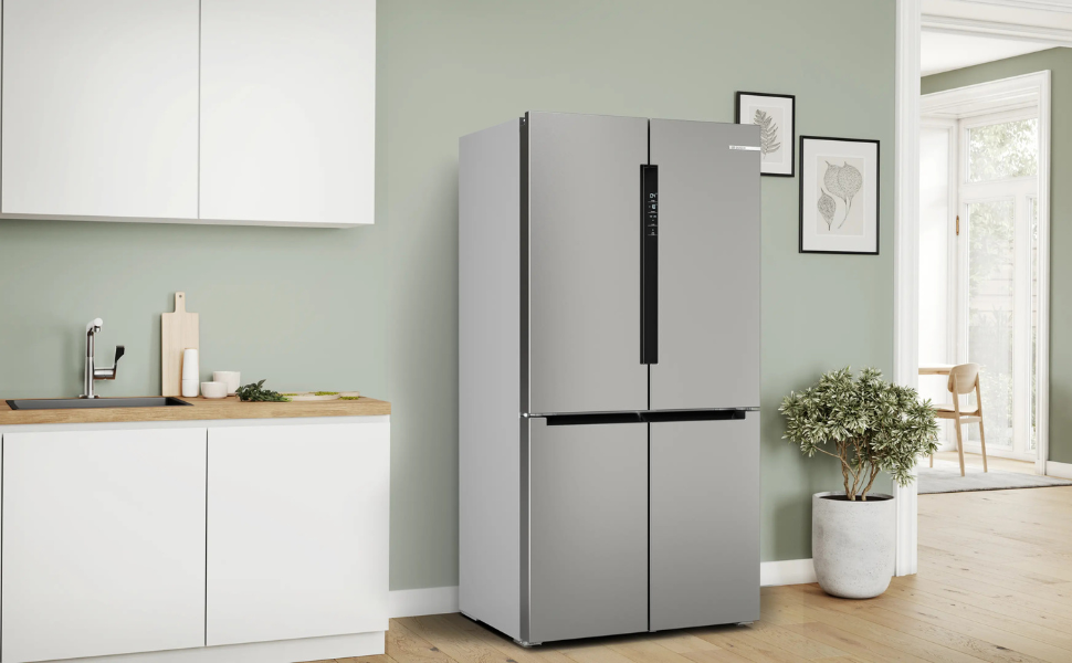 Intérieur de cuisine minimaliste moderne comprenant un grand réfrigérateur en acier inoxydable, des murs gris clair, des étagères flottantes en bois et des plantes en pot pour la décoration.