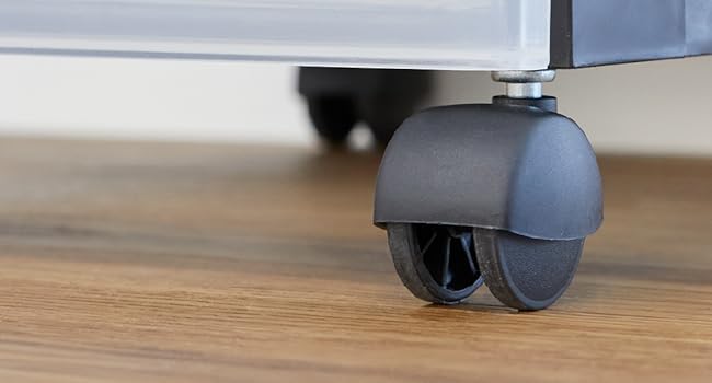 Gros plan d'une roulette en plastique gris sur un plancher en bois, montrant un mécanisme de roulement fluide.