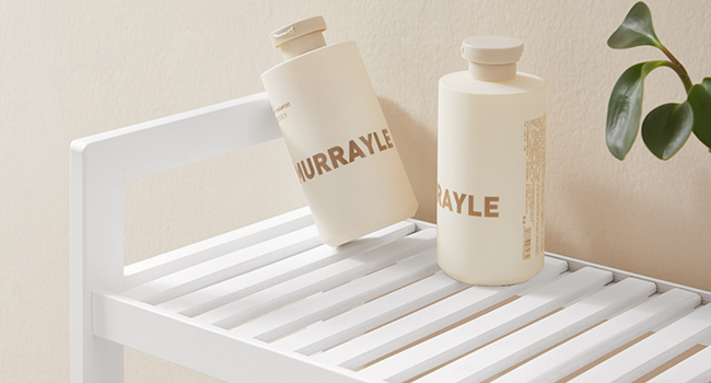 Bouteilles d'eau en plastique blanc avec étiquettes textuelles posées sur une étagère à lattes blanches ou un support contre un mur beige