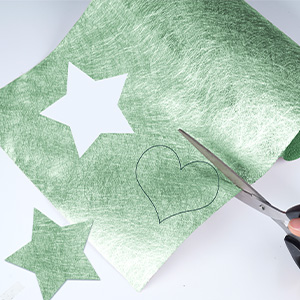 avec motif d'étoiles blanches. Ciseaux visibles, découpant une forme de cœur dans le matériau.