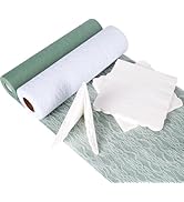 Présentation de matériaux en papier ou en tissu de couleurs blanc et vert sauge, avec des ciseaux visibles. Les matériaux semblent être disposés sur une surface texturée.