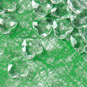 Gros plan d'objets transparents de forme irrégulière éparpillés sur un fond vert vif avec une texture semblable à une toile