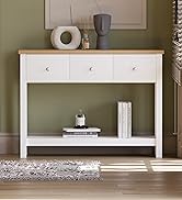 Console blanche et bois avec trois tiroirs et une étagère inférieure. Décoré avec des objets décoratifs sur le dessus contre un mur végétal