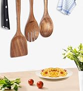 Ustensiles de cuisine en bois, y compris des cuillères et des spatules accrochées au mur, avec un plat à pâtes et des légumes frais visibles sur le comptoir ci-dessous.