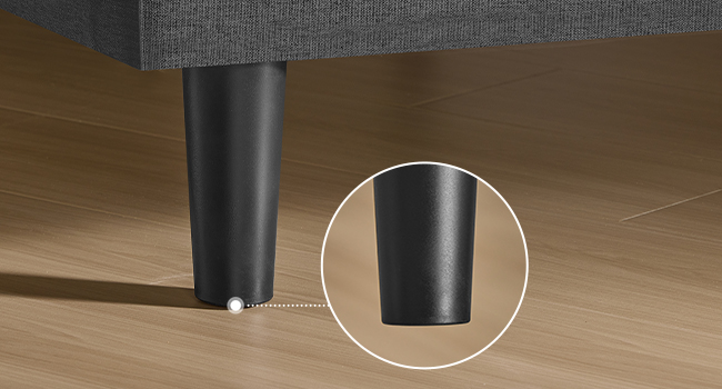 Gros plan d'un pied de meuble cylindrique noir sur un plancher en bois. Un insert circulaire met en valeur les détails de la jambe, laissant apparaître une finition mate et lisse