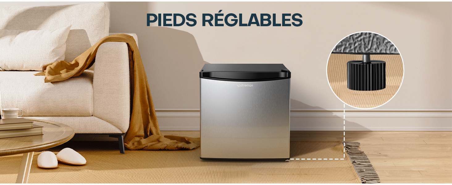 Appareil en forme de cube argenté avec pieds réglables, présenté dans un salon à côté d'un canapé. Gros plan du mécanisme du pied affiché.