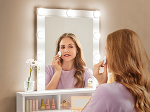 une femme qui se maquille devant un miroir.
