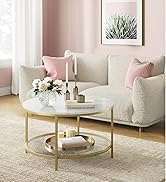 avec plateau en marbre blanc et structure en métal doré, à deux niveaux. Placé devant un canapé de couleur crème avec des coussins roses