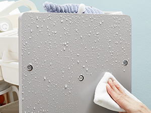 Des gouttelettes d'eau sur une surface gris clair sont essuyées avec un chiffon blanc, démontrant des propriétés de résistance à l'eau ou à l'eau.