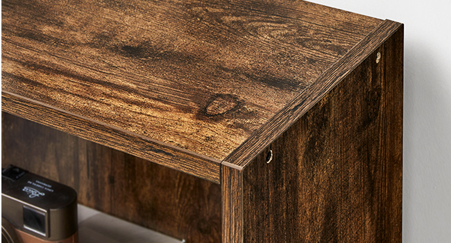 Gros plan d'un meuble en bois rustique, montrant une surface texturée brun foncé avec un grain de bois visible. Les détails des coins révèlent la menuiserie et la construction