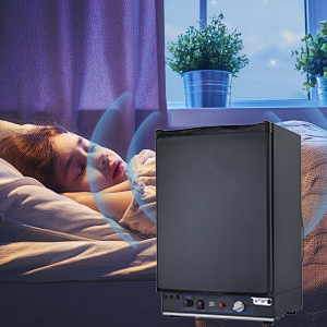 Mini-réfrigérateur ou unité de refroidissement compact noir illustré dans une chambre à coucher avec des plantes en pot en arrière-plan