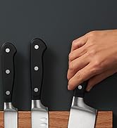 la main d'une personne tenant un couteau sur une planche de bois.