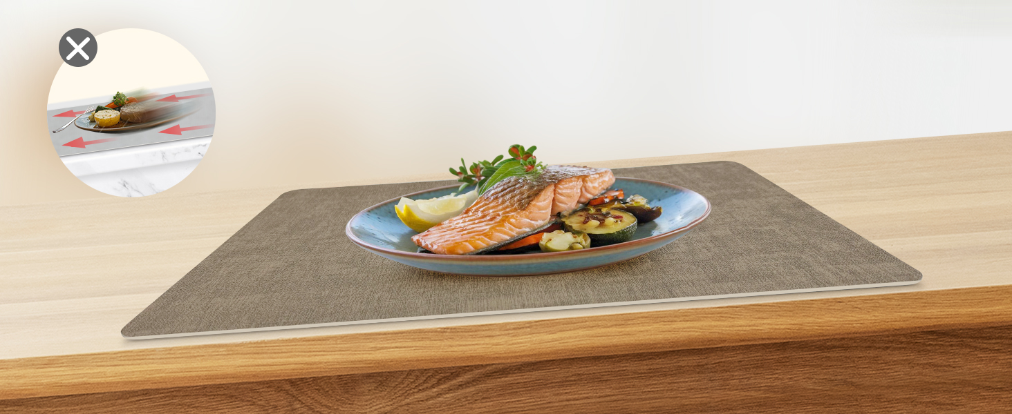 Image rapprochée d'une surface ou d'un tapis texturé gris, semblant être posé sur une table ou un comptoir en bois avec des assiettes de nourriture visibles en arrière-plan.