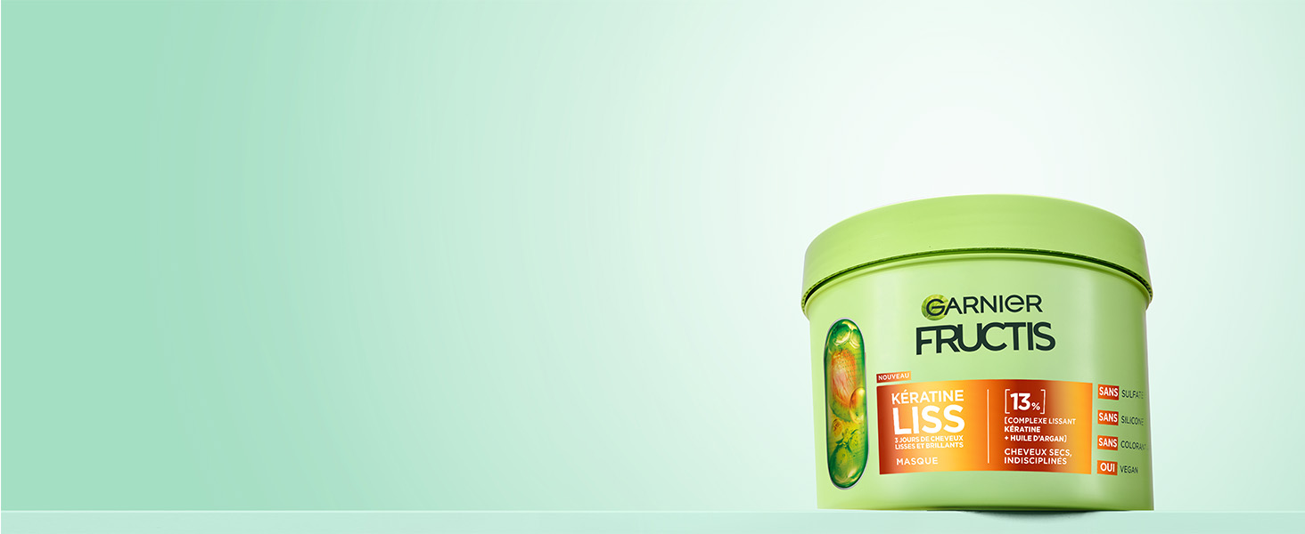 Le texte indique « Garnier Fructis ». Pot de produit teinté en vert sur fond clair avec un éclairage tamisé.