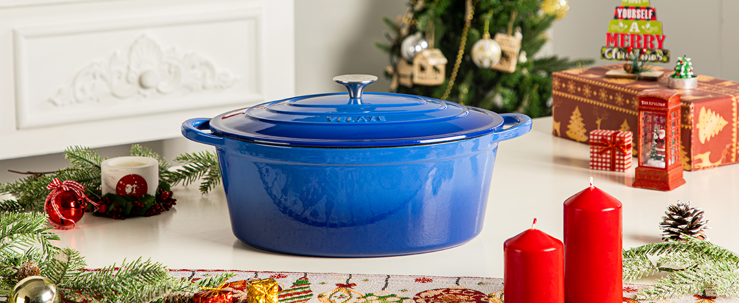 Grand four hollandais en fonte émaillée bleu cobalt avec couvercle affiché sur un comptoir blanc avec décorations de fêtes et bougies rouges