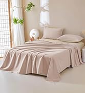 sur un lit, comprenant un drap-housse, un drap plat et des taies d'oreiller. La parure de lit a un aspect doux et texturé dans une couleur neutre.