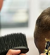 Gros plan d'une tondeuse à cheveux en cours d'utilisation, coupant les cheveux courts. La main du coiffeur est visible et tient l'appareil contre la tête d'un client