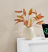 Feuilles d'automne artificielles dans un vase texturé blanc sur une surface blanche. Une montre connectée dotée d'un écran vert brillant est visible dans le coin