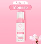Flacon rose de produit de soin Sakura Mousse sur fond rose. Distributeur de mousse blanc avec logo floral. Fleur de cerisier dans un coin.