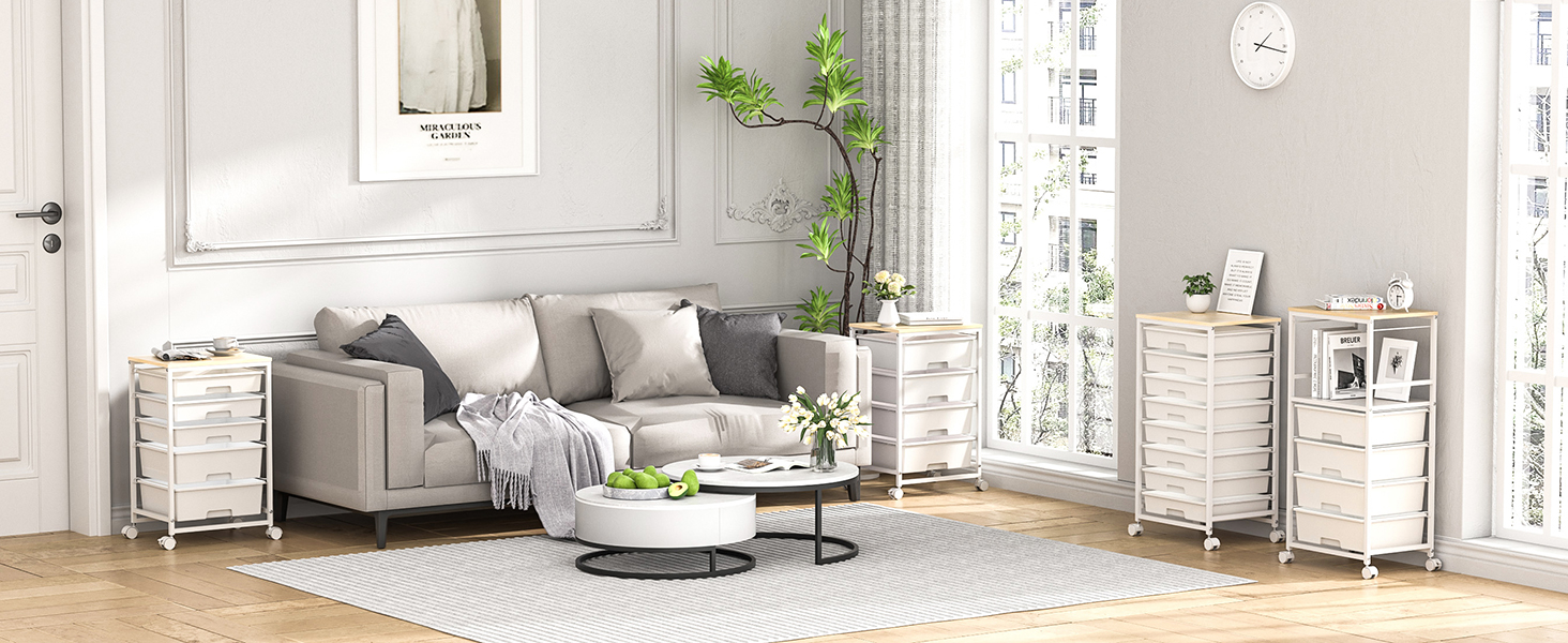 Salon moderne avec canapé gris, meubles de rangement blancs, tables basses rondes gigognes, tapis rayé et plante grimpante près de fenêtres lumineuses. Cette chambre est dotée de parquet en bois clair et de murs blancs.
