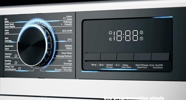 Gros plan du panneau de commande de la machine à laver avec grand cadran lumineux et affichage numérique indiquant 18:08. Le panneau comporte plusieurs options de cycle de lavage et de réglages de température.