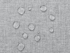 Gros plan d'un tissu gris avec des gouttelettes d'eau perlant à sa surface, démontrant des propriétés de résistance à l'eau ou à l'eau