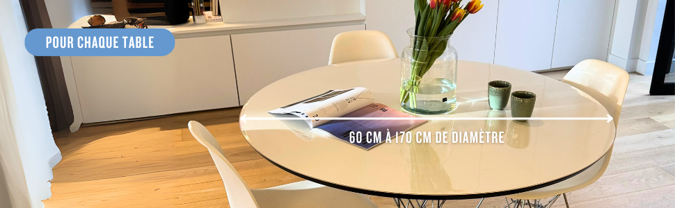 Personne utilisant un ordinateur portable assise à une table en bois avec vue sur la fenêtre. Aménagement de l'espace de travail épuré et minimaliste avec tasse à café blanche.