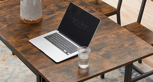 argenté avec écran noir affichant « 10:37 » sur une table en bois avec un verre d'eau et un objet en céramique blanche à proximité