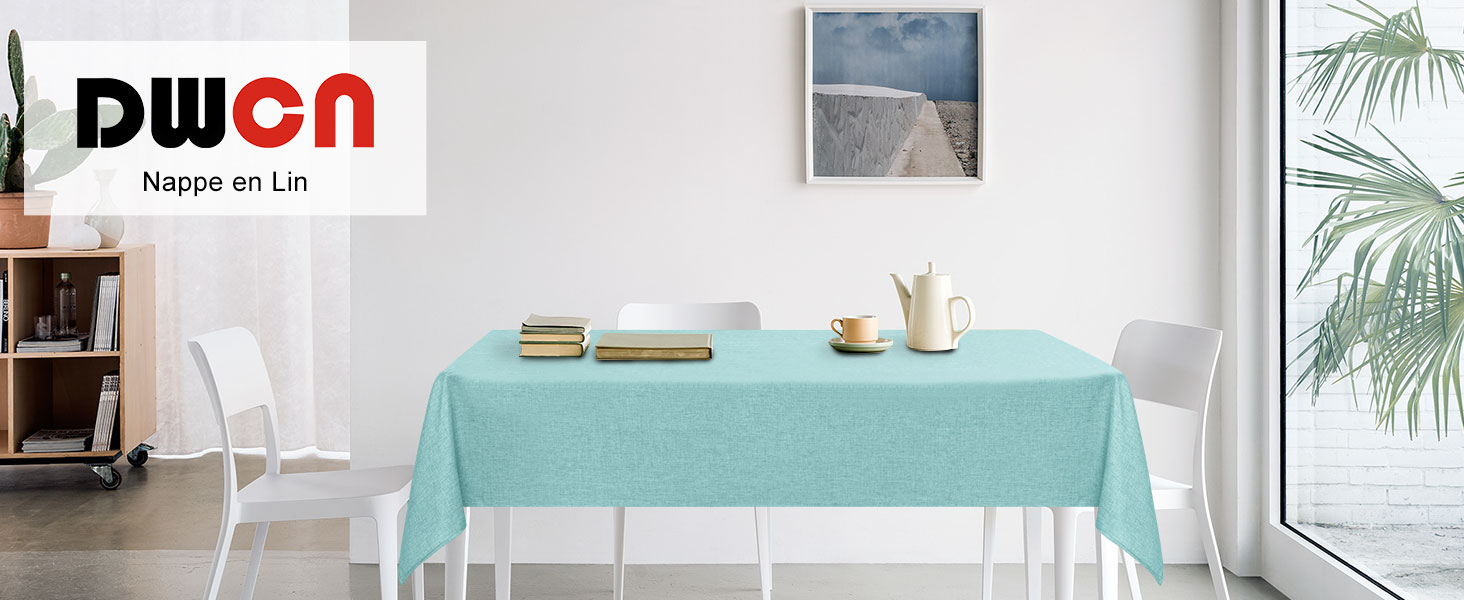 Configuration de la salle à manger avec une nappe vert menthe sur une table rectangulaire, des murs blancs et une grande fenêtre avec