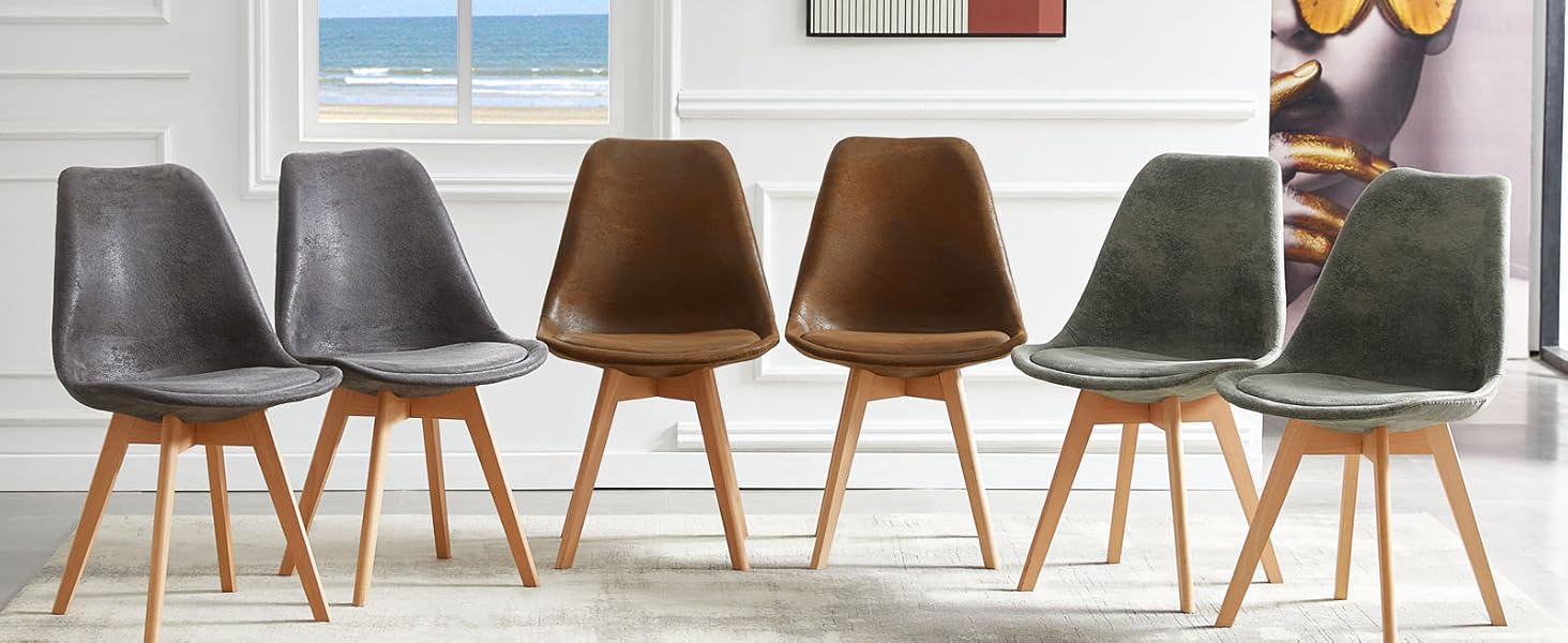 Six chaises de salle à manger de style milieu du siècle de différentes couleurs, disposées dans une pièce lumineuse avec vue sur l'océan et art mural abstrait