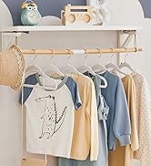 avec tringle en bois présentant un assortiment de chemises pour enfants aux couleurs pastel, y compris des options bleu et crème avec des imprimés graphiques