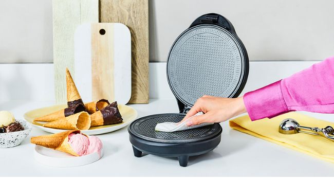 Personne nettoyant la surface de cuisson de l'appariel à cornet de glace Tristar