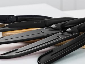 Plusieurs fers plats ou fers à lisser de couleurs noires et métalliques, disposés sur une surface en bois. Les appareils présentent des designs élégants et allongés avec des plaques lisses et des bords incurvés.