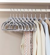 Ensemble de cintres uniformes en velours gris avec un design incurvé et une surface antidérapante, rangés dans un placard avec des vêtements de couleur claire visibles