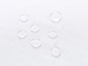 Plusieurs gouttelettes d'eau perlent sur une surface textile de couleur claire, démontrant des propriétés de résistance à l'eau ou d'imperméabilité