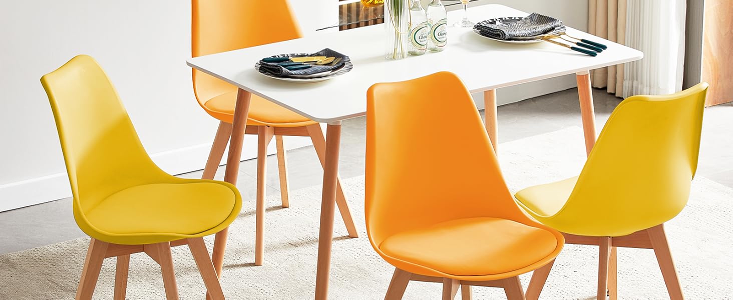 avec table rectangulaire blanche et quatre chaises - deux oranges et deux jaunes - avec pieds en bois dans une pièce lumineuse.