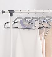 Porte-vêtements blanc avec plusieurs cintres contenant des vêtements de couleur claire, y compris des chemises et des robes