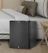 un lit avec un réfrigérateur noir assis à côté d'un lit.