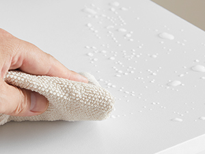 Utilisez à la main un chiffon texturé pour essuyer une surface contenant des gouttelettes d'eau, démontrant ainsi une action nettoyante ou séchante