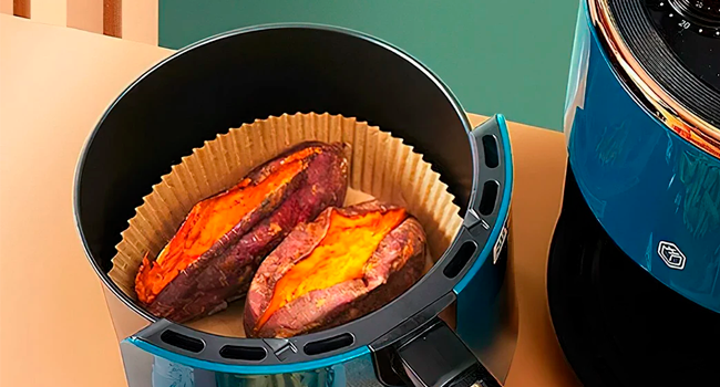 contenant deux moitiés de patate douce cuite à la peau croustillante et caramélisée. Vue partielle de l'unité de friteuse à air visible.