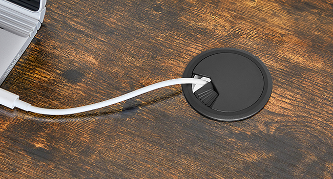 Chargeur sans fil rond noir avec câble blanc, placé sur une surface en bois foncé.