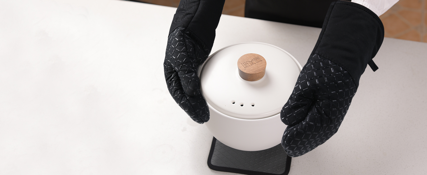 Des mains portant des gants noirs texturés tiennent un contenant circulaire blanc percé de petits trous dans le couvercle et doté d'une poignée en bois.