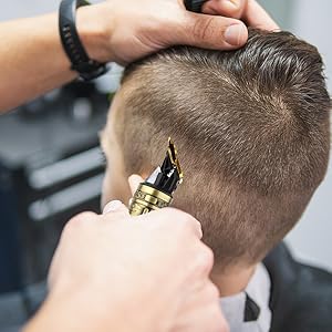 Gros plan d'une coupe de cheveux professionnelle à l'aide d'une tondeuse électrique dorée sur cheveux courts